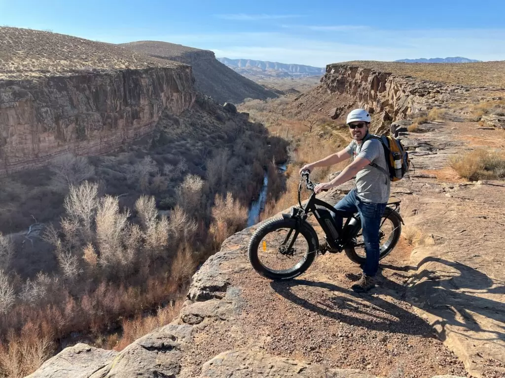 man in white shirt riding on black mountain bike on brown rocky mountain during daytime